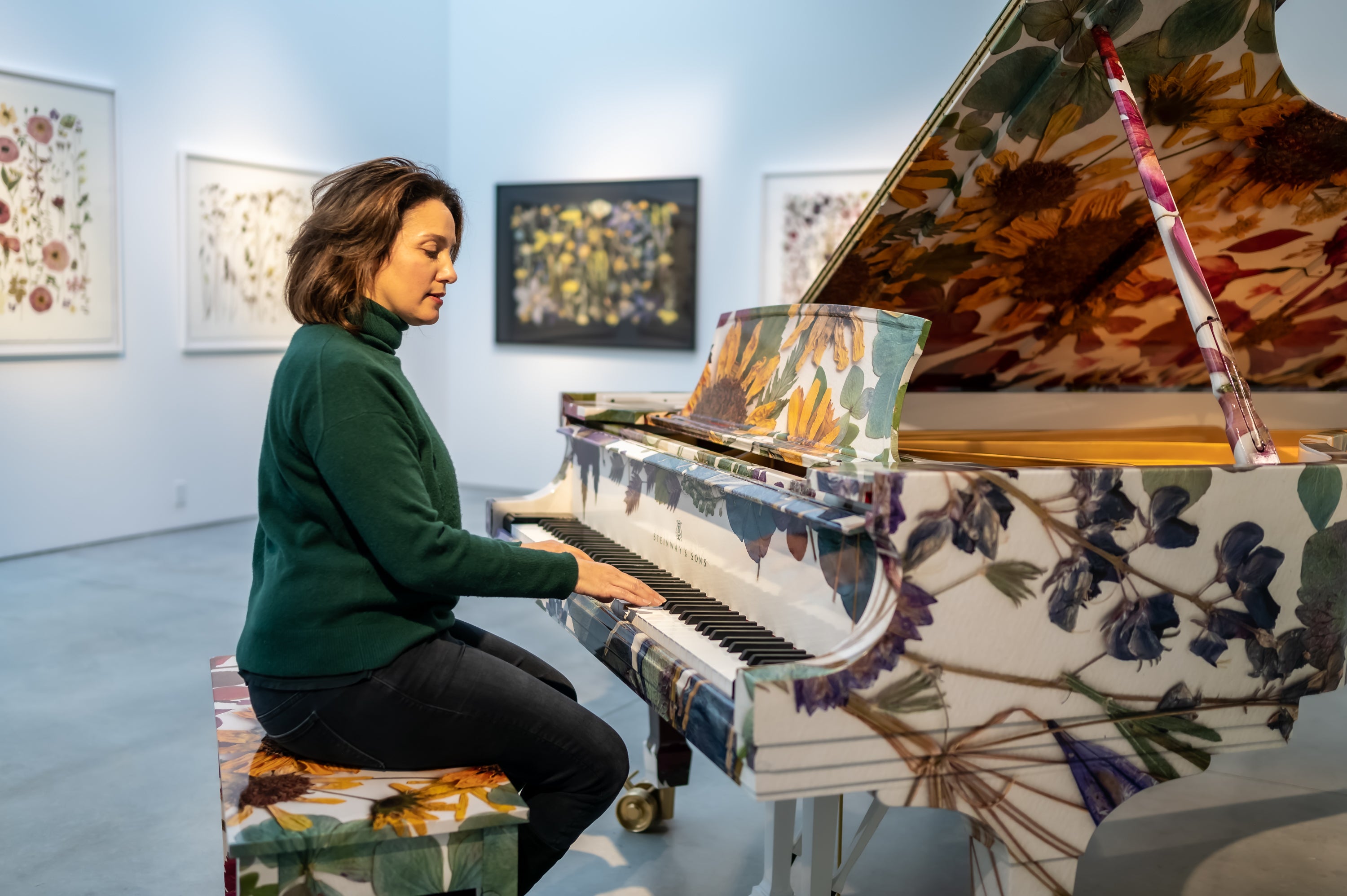Woman playing a floral-patterned piano in an art gallery setting