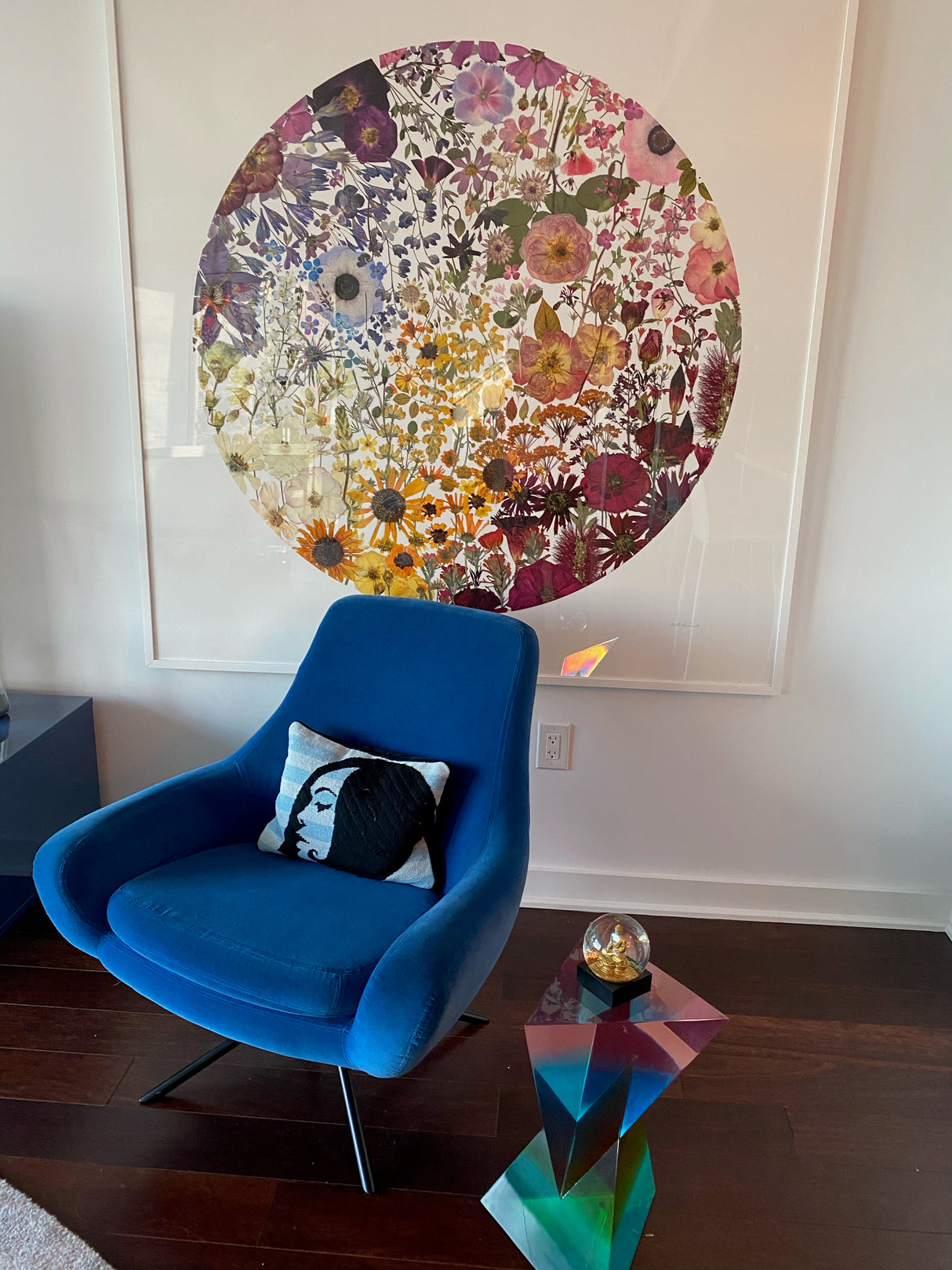 Blue chair with a colorful floral painting in a room.