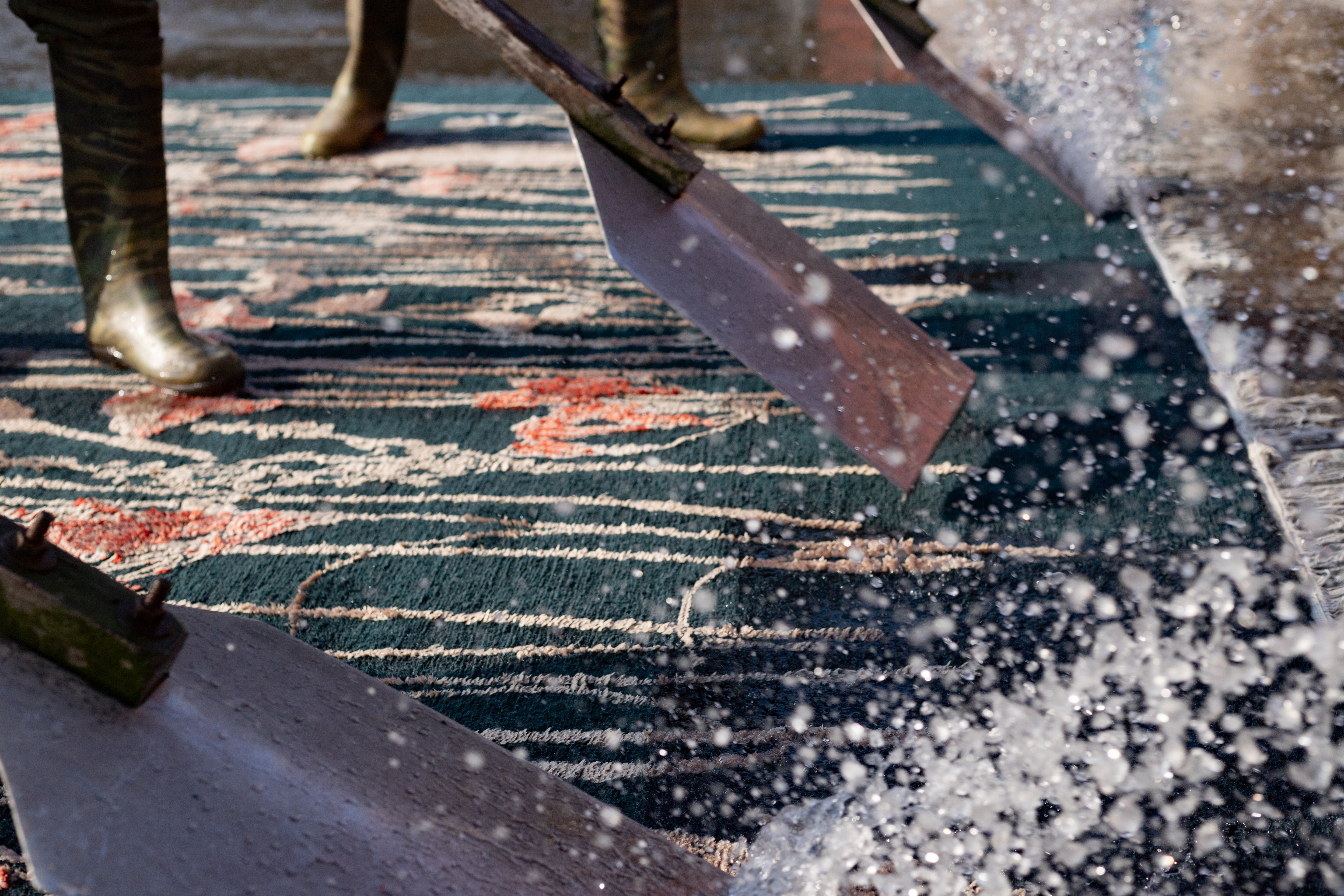 Cleaning tool being used on a patterned rug with visible dirt and stains.