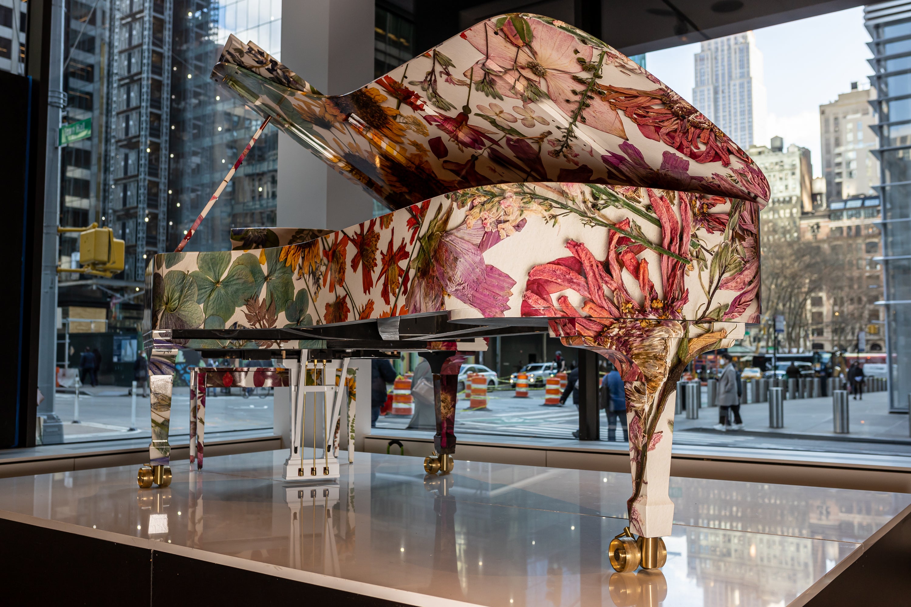 Colorful floral-patterned piano in an urban setting with cityscape in the background