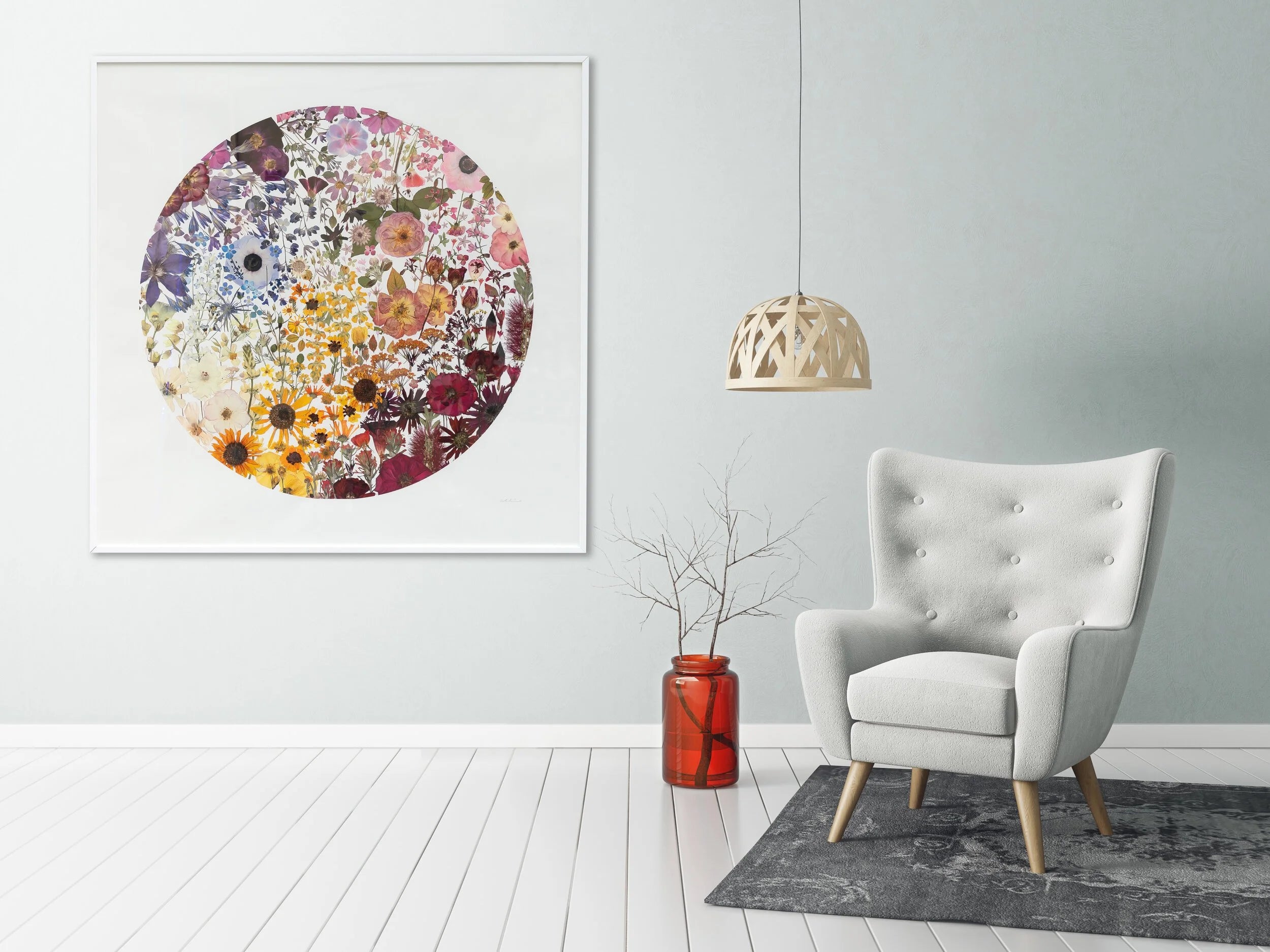 Decorative floral wall art above a gray armchair in a room with a light gray wall and wooden floor.
