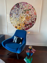 Blue chair with a colorful floral painting in a room.