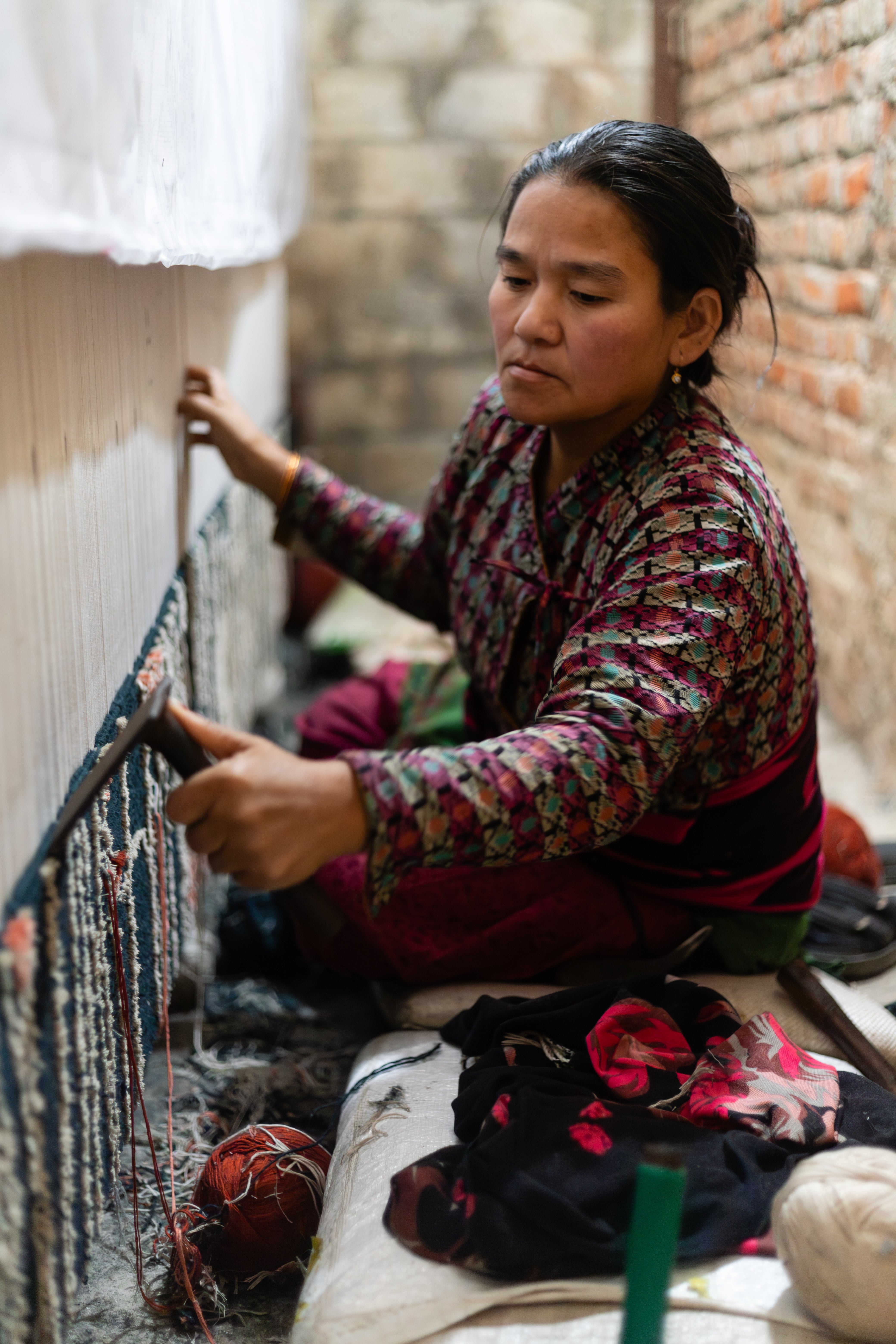 Woman weaving on a loom in a traditional setting