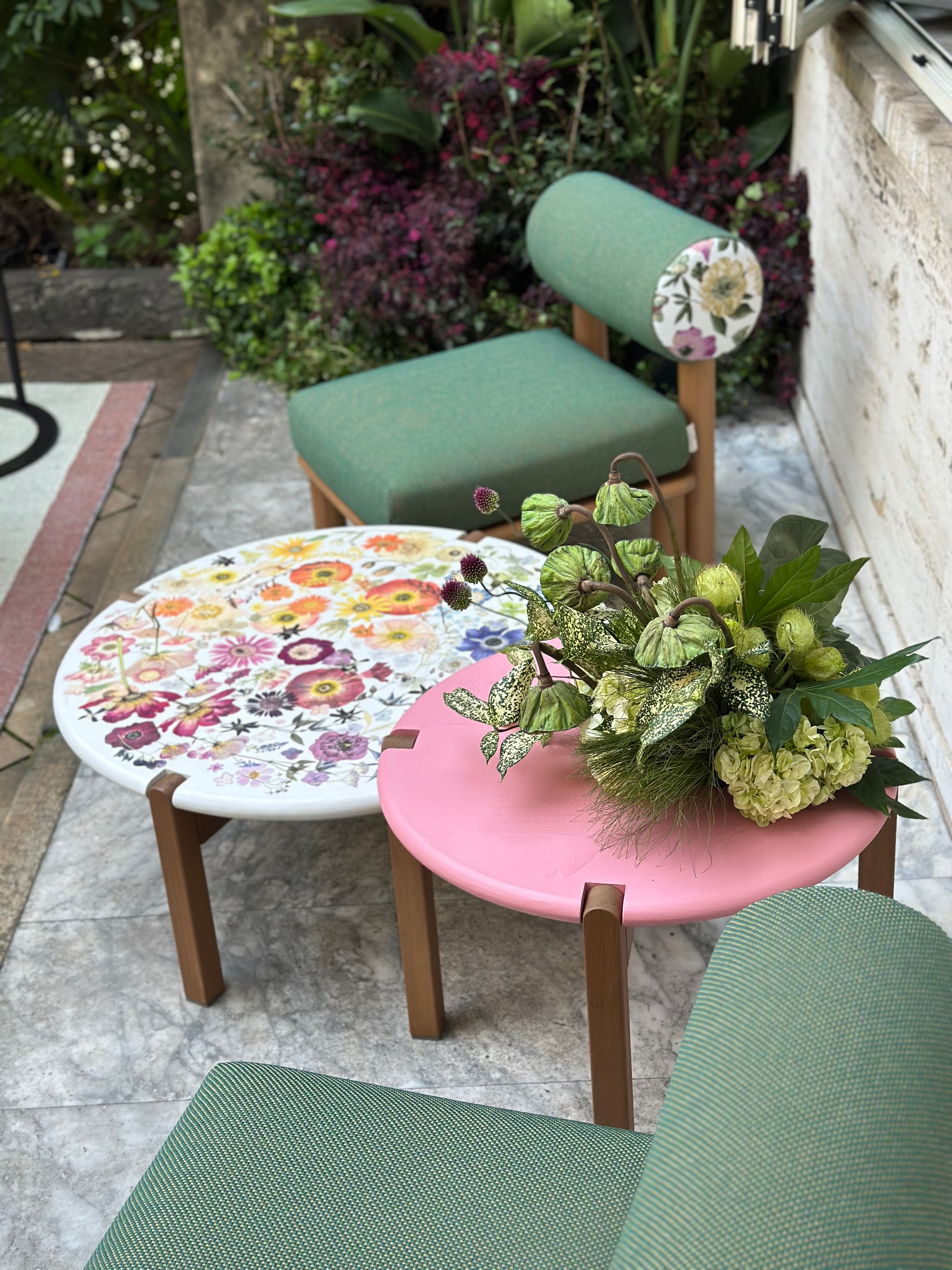 Outdoor setting with floral-patterned table and chairs, surrounded by plants.